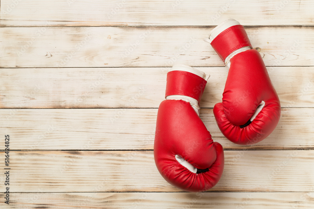 Red boxing gloves on wooden background, top view