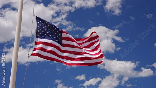American flag waving in slow motion at half mast on partly cloudy day. photo
