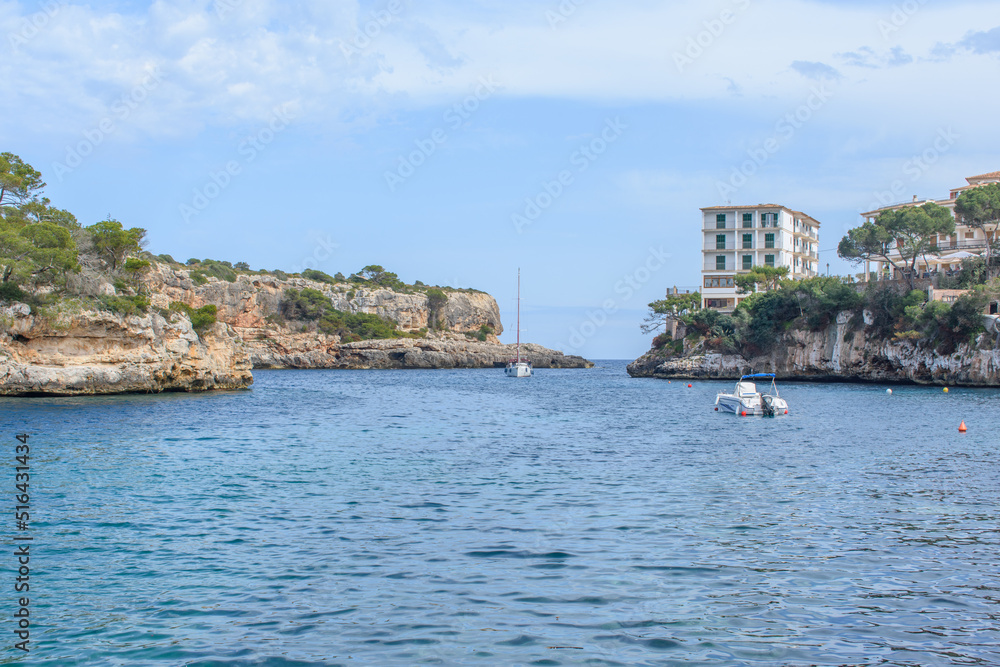 Coastal cliffs, boat and yacht in bay of Cala Figuera