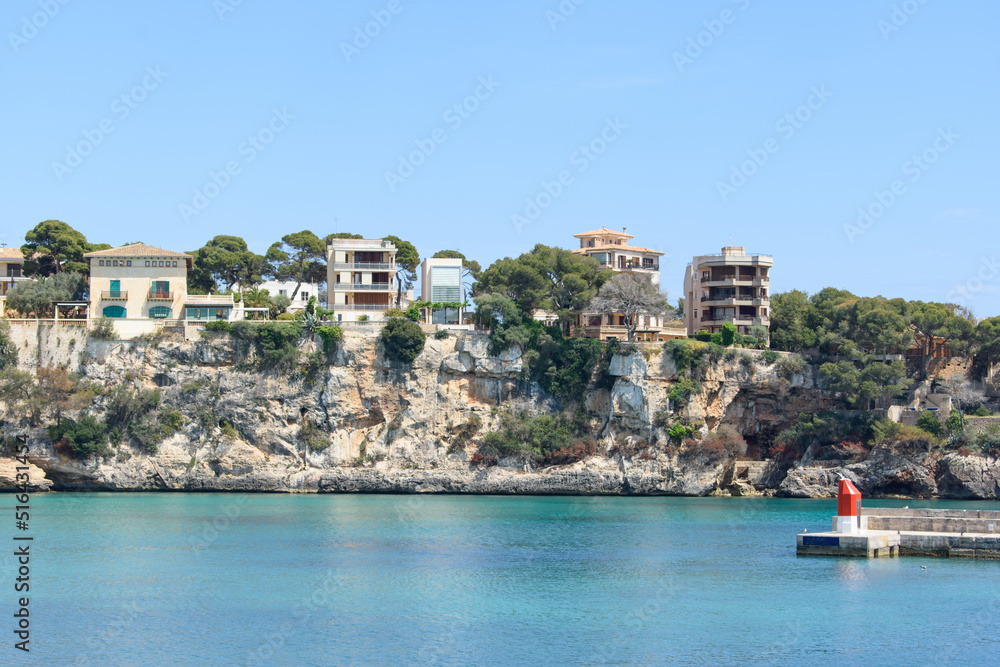 Houses on top of the coastal cliffs in Porto Cristo. Calm, turquoise sea water.