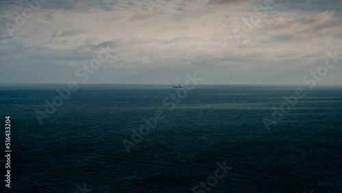 Fotografie, Obraz The blue cloudy sky and the Irish Sea merging into the horizon and a ship at a d