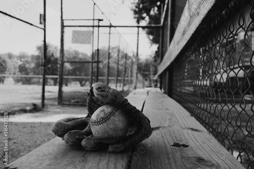 фотографія Old used baseball equipment on field dugout bench in black and white closeup