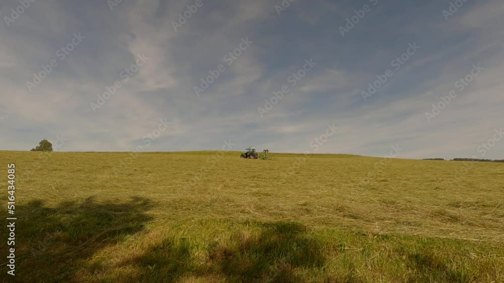 The theme of farming, agricultural farming in the Bavarian region of Germany in the summer. A farmer cultivates the land with the help of farm equipment. Mowing grass for hay The theme of farming, agricultural farming in the Bavarian region of Germany in the summer. A farmer cultivates the land with the help of farm equipment. Mowing grass for hay