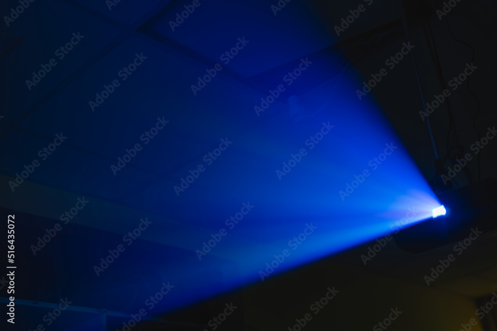 projector spotlight blue color , smoke texture background . light beam screening and glowing for movie cinema and film multimedia production in dark black room at night . wide lens showing, copy space