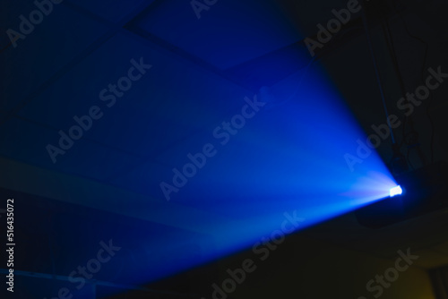 Obraz na płótnie projector spotlight blue color , smoke texture background . light beam screening and glowing for movie cinema and film multimedia production in dark black room at night . wide lens showing, copy space w salonie