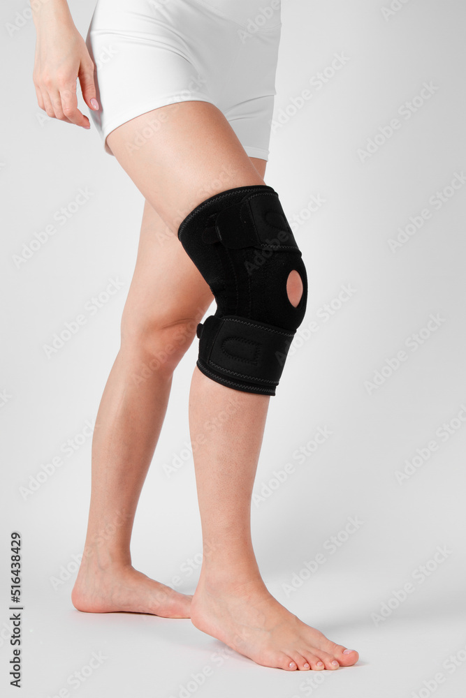 Knee Support Brace on leg isolated on white background. Elastic orthopedic orthosis. Anatomic braces for knee fixation, injuries and pain. Protective knee joint bandage sleeve. Trauma, rehabilitation Knee Support Brace on leg isolated on white background. Elastic orthopedic orthosis. Anatomic braces for knee fixation, injuries and pain. Protective knee joint bandage sleeve. Trauma, rehabilitation