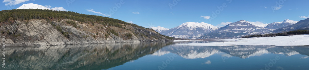 panoramic view of serre ponçon lake in the mountains of the alps france with perfect mirror reflection in winter