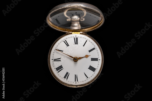 Dial of silver antique pocket watch with an open glass lid on isolated black background. Old mechanical clock. Round retro pocketwatch with minute and hour hands. Vintage expensive watch.