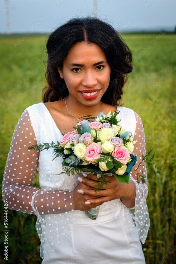 beautiful african-american bride standing in white gown and holding bouquet of roses beautiful african-american bride standing in white gown and holding bouquet of roses
