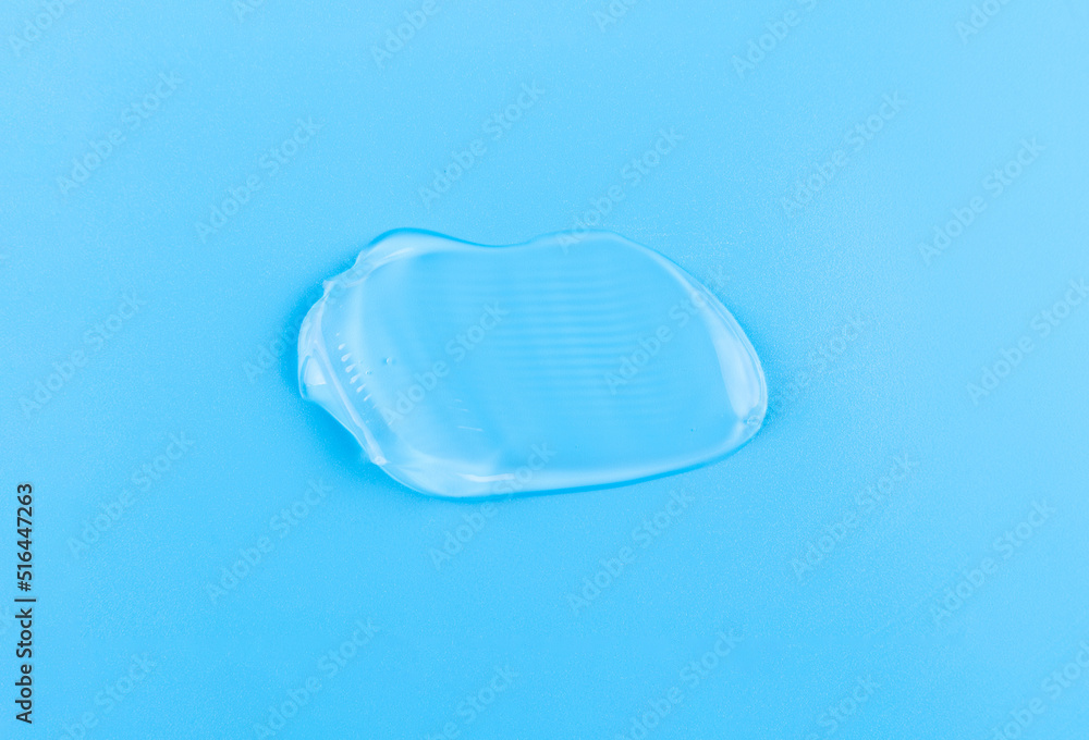 Smear of cosmetology transparent product for face treatment. Drop of cream on blue background. Lotion or mask. Beauty wellness and professional skincare concept. Smear of cosmetology transparent product for face treatment. Drop of cream on blue background. Lotion or mask. Beauty wellness and professional skincare concept.