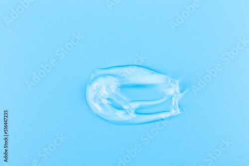 Smear of cosmetology transparent product for face treatment. Drop of cream on blue background. Lotion or mask. Beauty wellness and professional skincare concept.