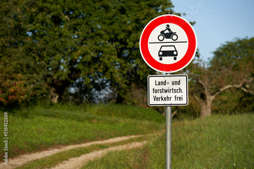 Red prohibition sign for cars and motorcycles. Signal on a dirt road. Translation on Sign: Agricultural and forestry traffic free.