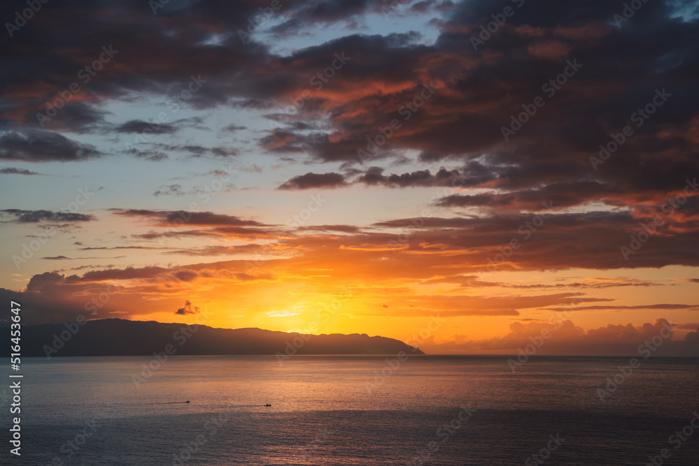 Dramatic sunset cloudy orange sky over the island La Gomera from Tenerife. View of Atlantic ocean and the sea of Canary islands, Spain.