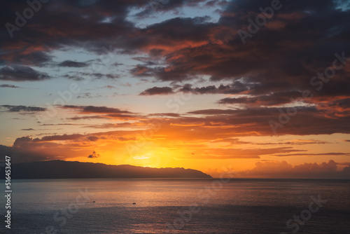 Dramatic sunset cloudy orange sky over the island La Gomera from Tenerife. View of Atlantic ocean and the sea of Canary islands, Spain.