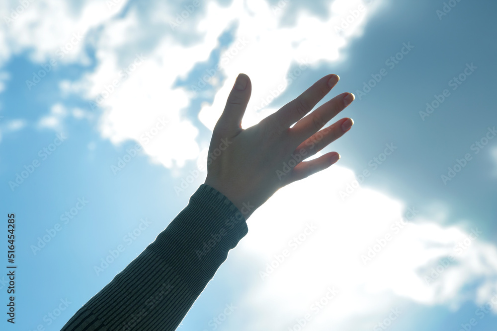 raised woman hand against the sunny sky