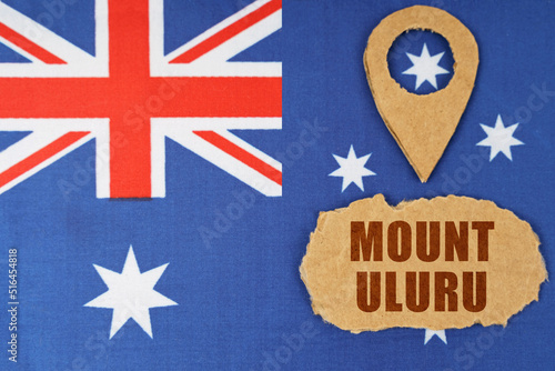 The flag of Australia has a geolocation symbol and a sign with the inscription - Mount Uluru