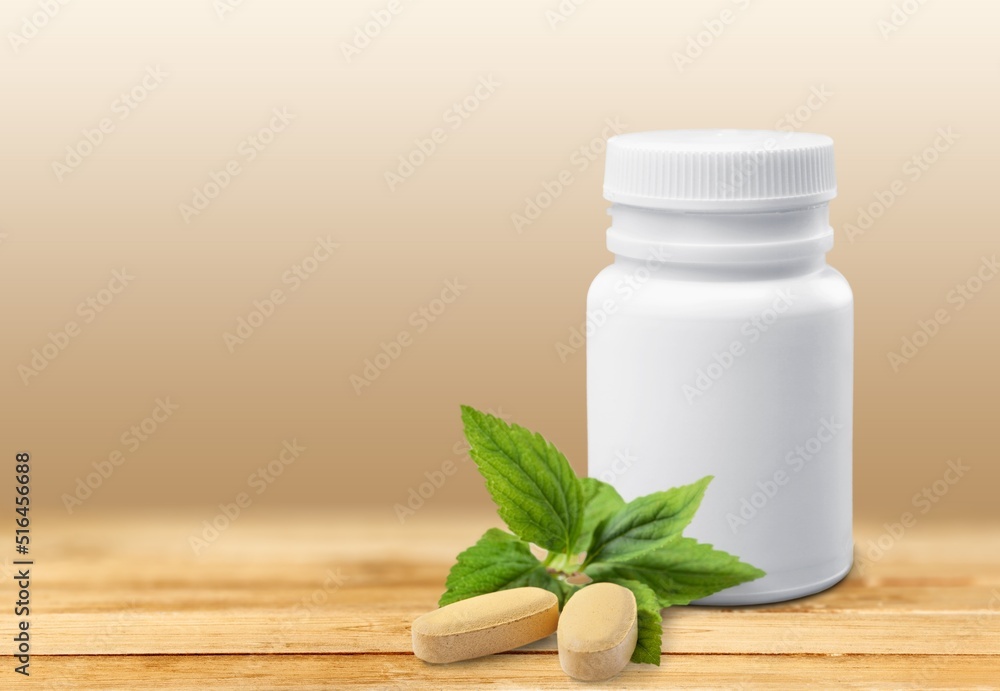 A bottle for pills and vitamins with green leaves, natural organic bio supplement concept A bottle for pills and vitamins with green leaves, natural organic bio supplement concept