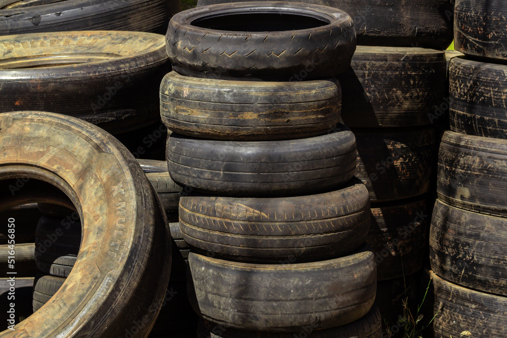Muitos pneus velhos e sujos de diferentes tamanhos empilhados em uma loja especializada. Pneus de borracha, usados. Muitos pneus velhos e sujos de diferentes tamanhos empilhados em uma loja especializada. Pneus de borracha, usados.