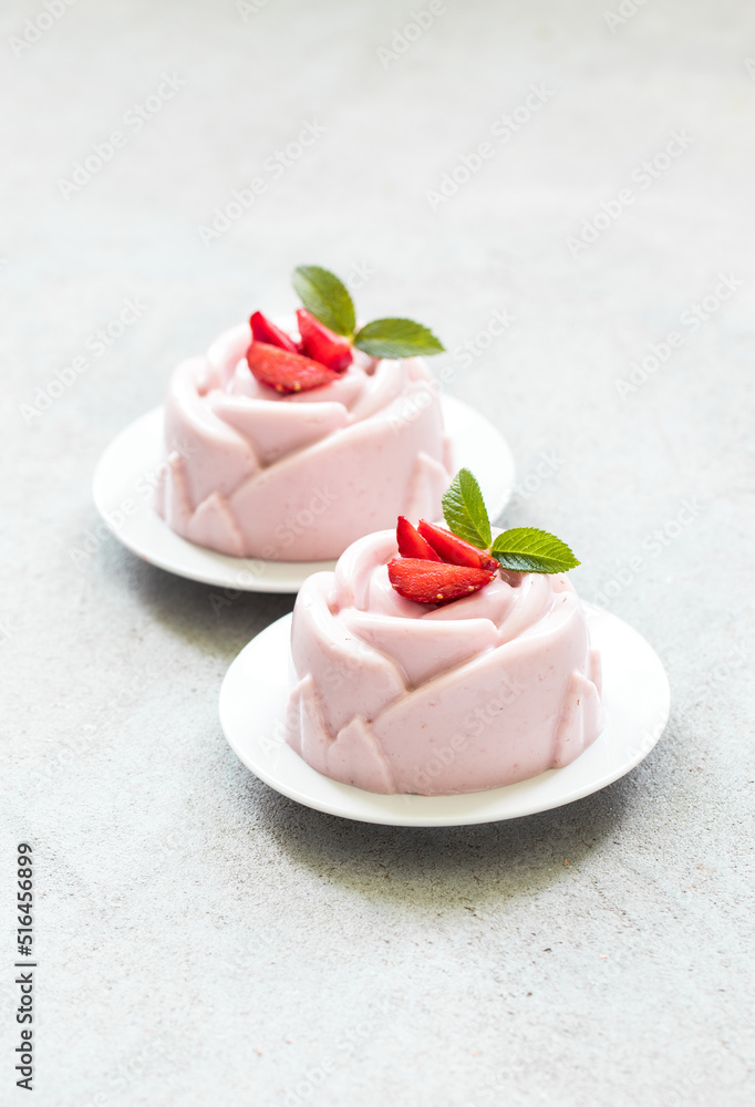 Vegan dessert. Strawberry cream pudding, Panna Cotta, in the shape of a rose, on a plate. Light grey background