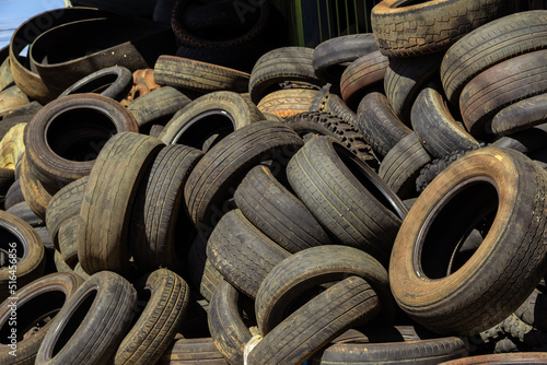 Muitos pneus velhos e sujos de diferentes tamanhos empilhados em uma loja especializada. Pneus de borracha, usados.