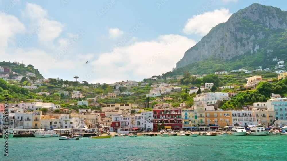 View of the Tyrrhenian sea coast in Capri, Italy. Classic buildings, piers with moored boats, greenery. View from a ship. Slow motion View of the Tyrrhenian sea coast in Capri, Italy. Classic buildings, piers with moored boats, greenery. View from a ship. Slow motion