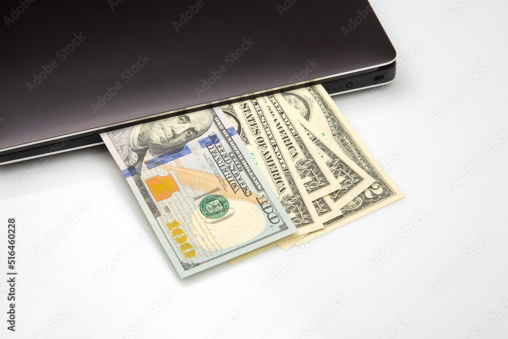 Dollar banknotes on a white background next to a laptop. Online business sale. Financial business success. Dollar banknotes on a white background next to a laptop. Online business sale. Financial business success.