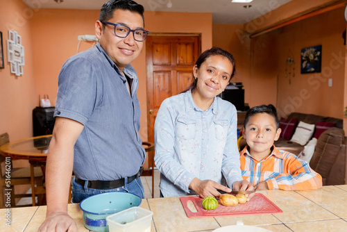 Small Latin family cooking healthy food at home - Hispanic housewife preparing food together with her husband and son
