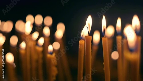 Close view of lots of burning candles with black background. Slow motion photo