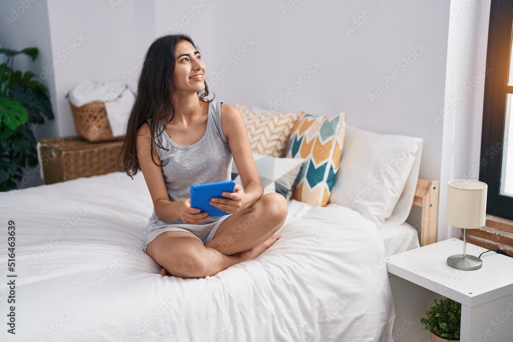 Young hispanic girl using touchpad sitting on bed at bedroom Young hispanic girl using touchpad sitting on bed at bedroom