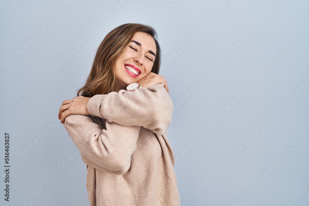 Young woman standing over isolated background hugging oneself happy and positive, smiling confident. self love and self care Young woman standing over isolated background hugging oneself happy and positive, smiling confident. self love and self care