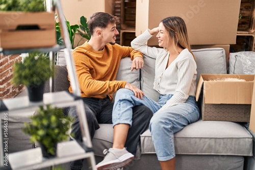 Young man and woman couple having conversation sitting on sofa at new home
