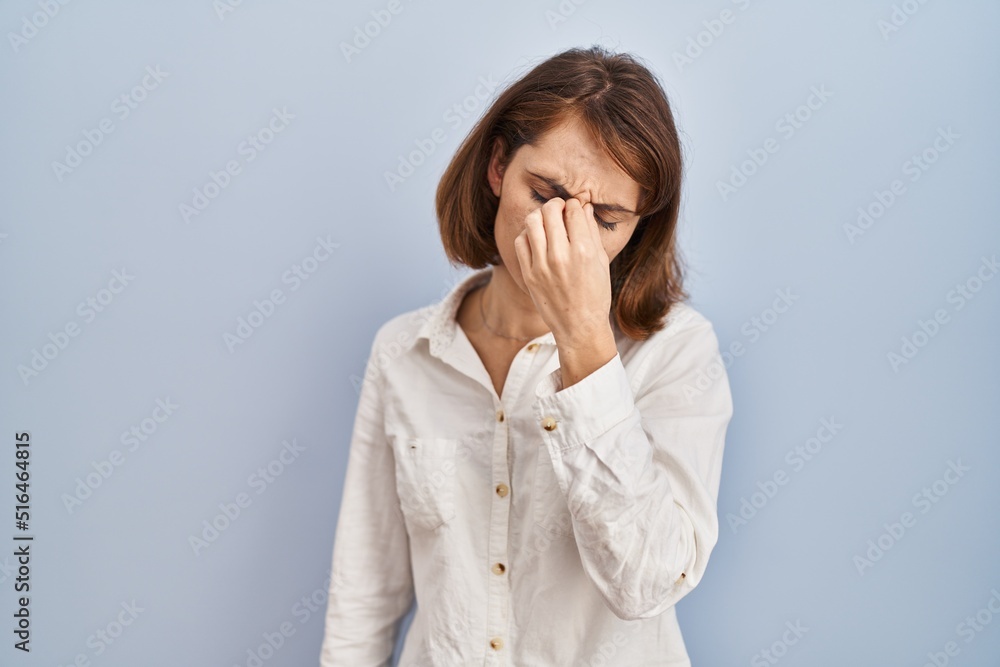 Young beautiful woman standing casual over blue background tired rubbing nose and eyes feeling fatigue and headache. stress and frustration concept. Young beautiful woman standing casual over blue background tired rubbing nose and eyes feeling fatigue and headache. stress and frustration concept.