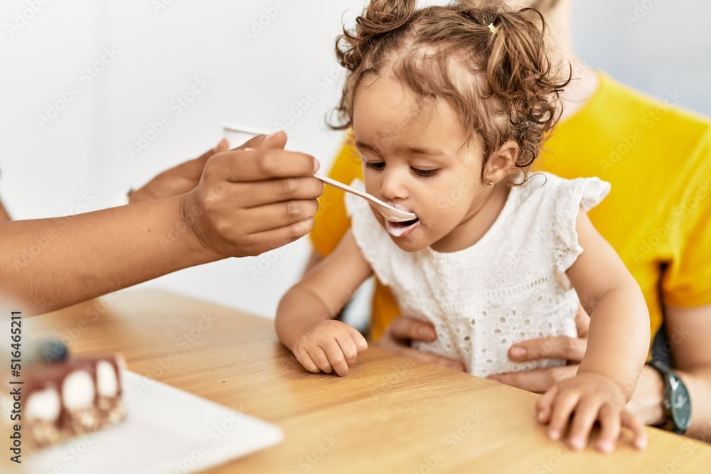 Naklejka premium Couple and daughter having breakfast sitting on table at home