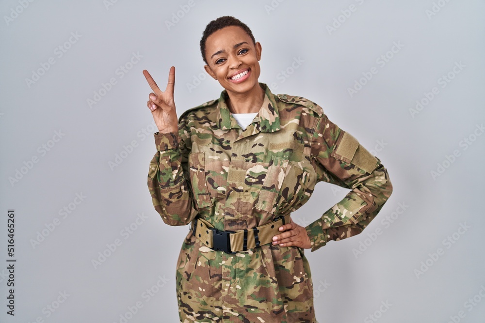 Beautiful african american woman wearing camouflage army uniform smiling looking to the camera showing fingers doing victory sign. number two. Beautiful african american woman wearing camouflage army uniform smiling looking to the camera showing fingers doing victory sign. number two.