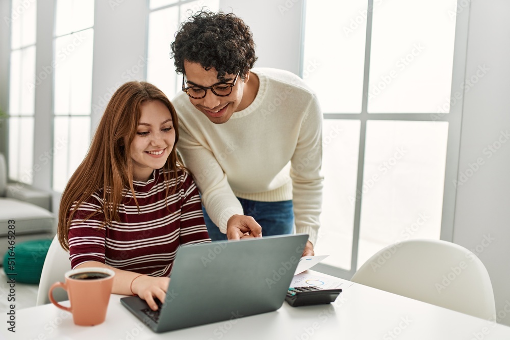 Young couple using laptop and drinking coffee sitting on the table at home. Young couple using laptop and drinking coffee sitting on the table at home.