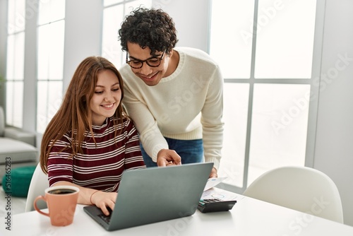 Young couple using laptop and drinking coffee sitting on the table at home.