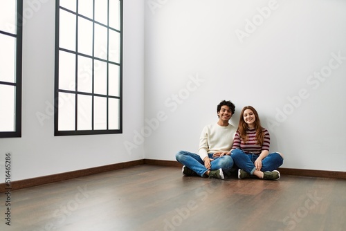 Young hispanic couple smiling happy sitting on the floor at empty new home. © Krakenimages.com