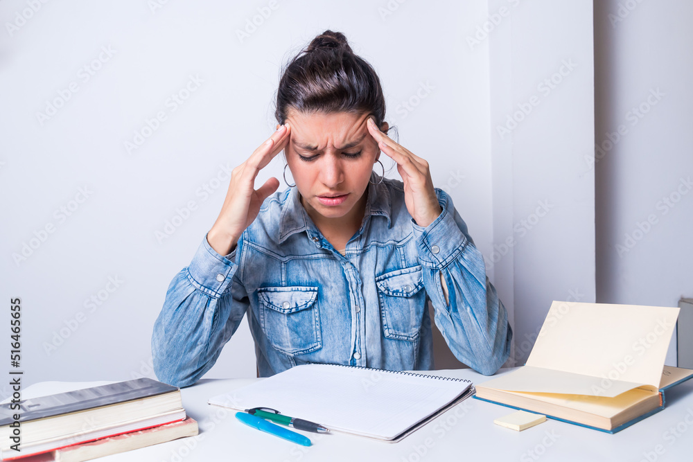 young latin woman, wearing glasses and books, very tired, holding her head and closing her eyes young latin woman, wearing glasses and books, very tired, holding her head and closing her eyes