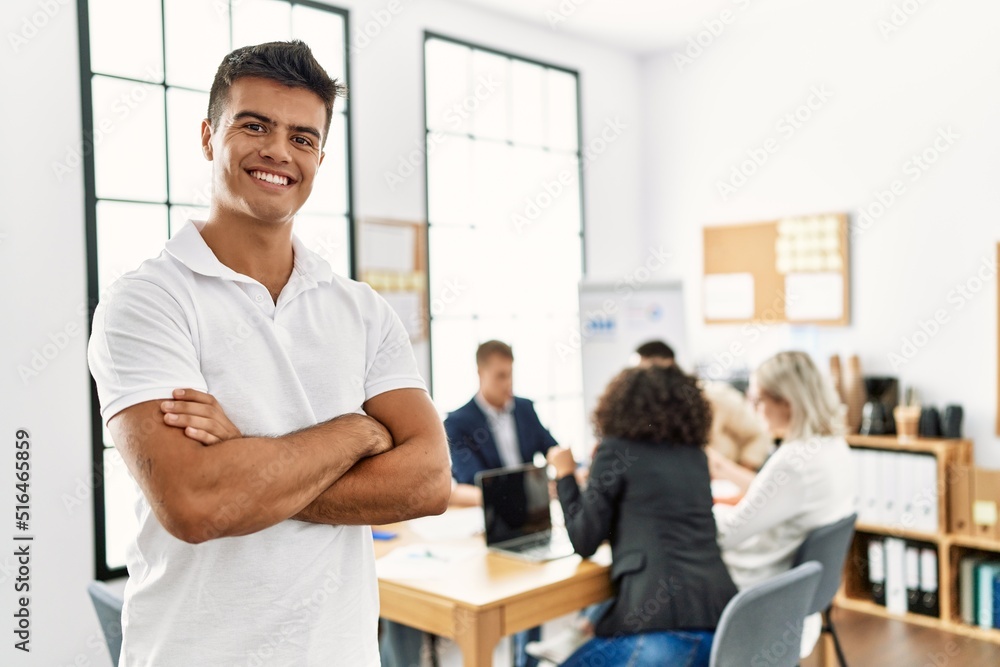 Young hispanic businessman smiling happy standing with arms crossed gesture at the office during business meeting. Young hispanic businessman smiling happy standing with arms crossed gesture at the office during business meeting.