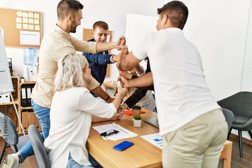 Group of business workers smiling happy celebrating making tower with fists together at the office. Group of business workers smiling happy celebrating making tower with fists together at the office.