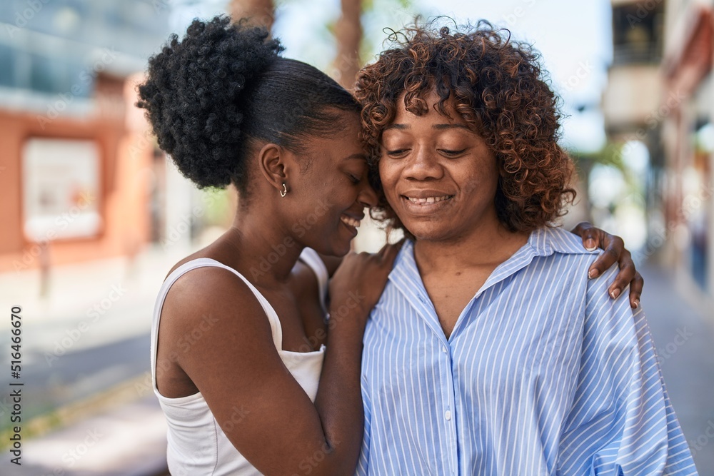 African american women mother and daughter hugging each other at street African american women mother and daughter hugging each other at street