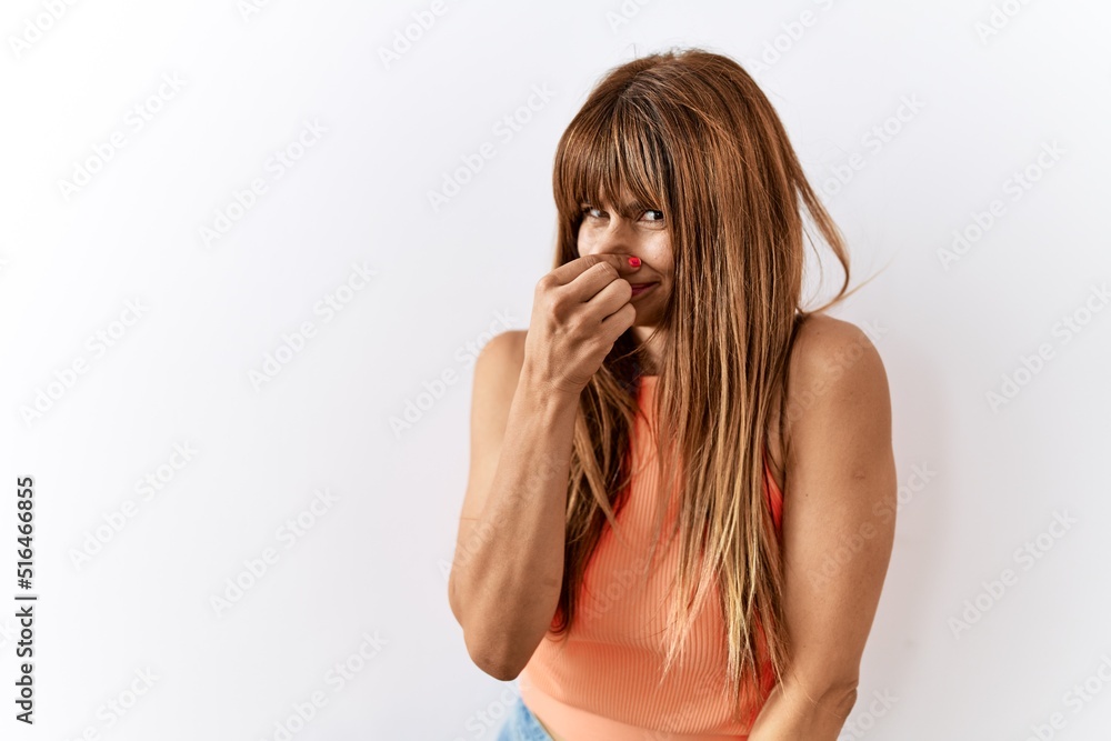 Hispanic woman with bang hairstyle standing over isolated background smelling something stinky and disgusting, intolerable smell, holding breath with fingers on nose. bad smell Hispanic woman with bang hairstyle standing over isolated background smelling something stinky and disgusting, intolerable smell, holding breath with fingers on nose. bad smell