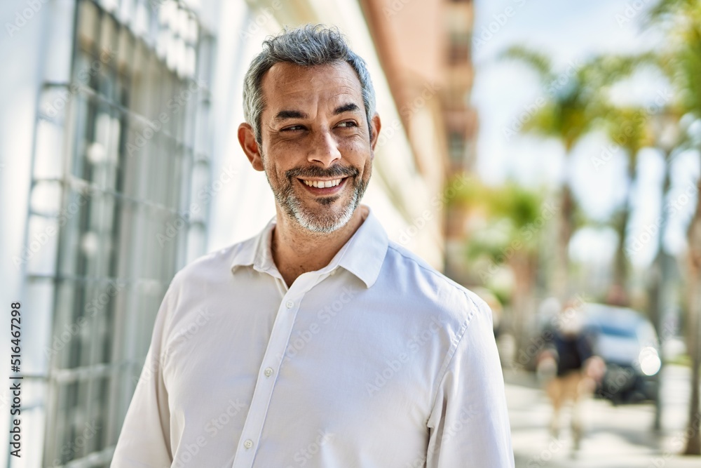Fototapeta premium Middle age grey-haired man smiling happy standing at the city.