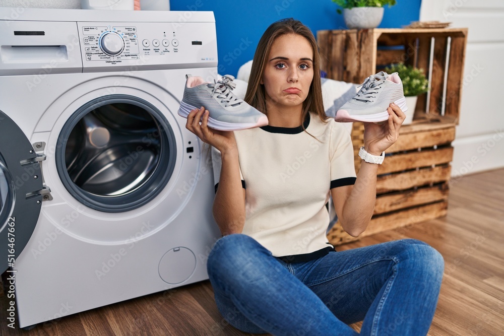young-woman-putting-sneakers-in-washing-machine-depressed-and-worry-for