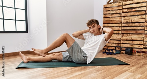 Young caucasian man training abs exercise at sport center