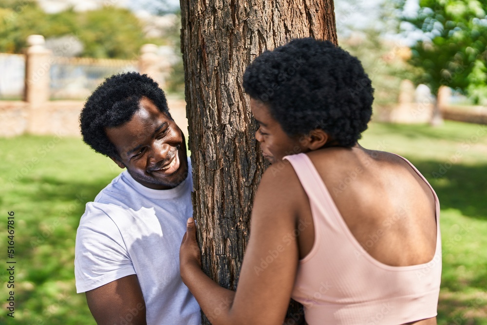 African american man and woman couple hugging tree at park African american man and woman couple hugging tree at park