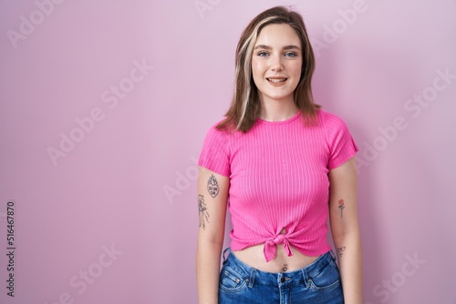 Blonde caucasian woman standing over pink background with a happy and cool smile on face. lucky person.