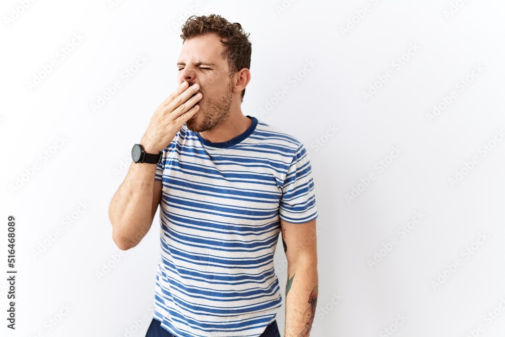 Handsome young man standing over isolated background bored yawning tired covering mouth with hand. restless and sleepiness. Handsome young man standing over isolated background bored yawning tired covering mouth with hand. restless and sleepiness.