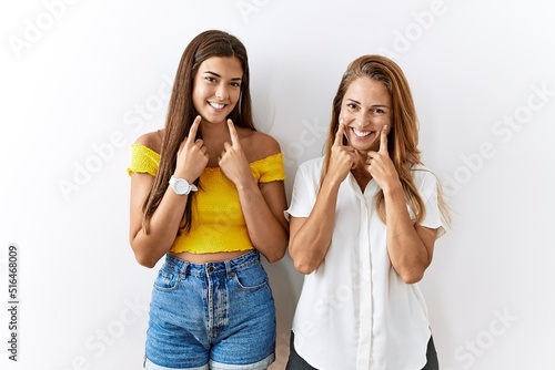 Mother and daughter together standing together over isolated background smiling with open mouth, fingers pointing and forcing cheerful smile