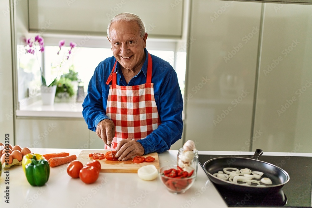 Senior man smiling confident cutting tomato at kitchen Senior man smiling confident cutting tomato at kitchen